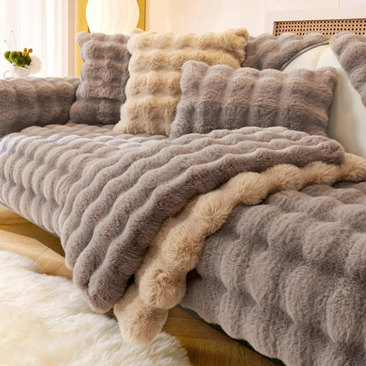 Een zachte, grijze Wagner - Fluffy Bankhoes Universeel, elegant gedrapeerd over een bed met witte en beige kussens in een gezellige, goed verlichte slaapkameromgeving van Act Design Shop.