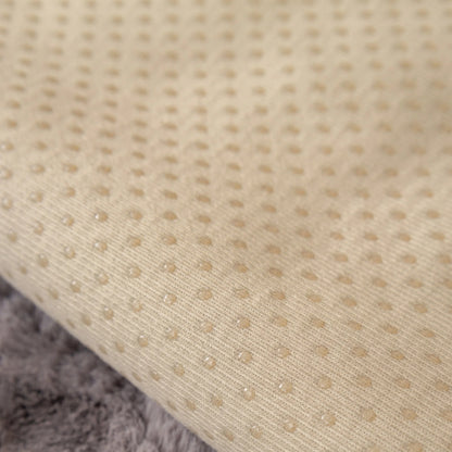 Close-up van een beige, Act Design Shop Wagner - Fluffy Bankhoes Universeel met een gestippeld structuurpatroon, weergegeven op een zachtgrijs oppervlak.